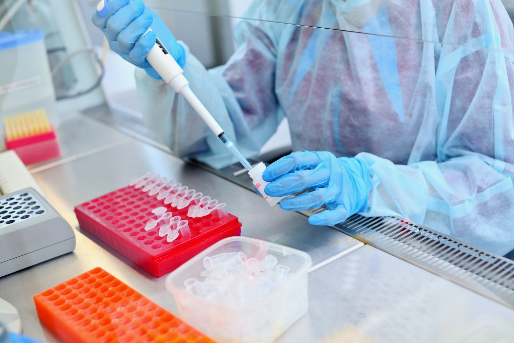 DNA testing scientist in sterile lab behind glass wall